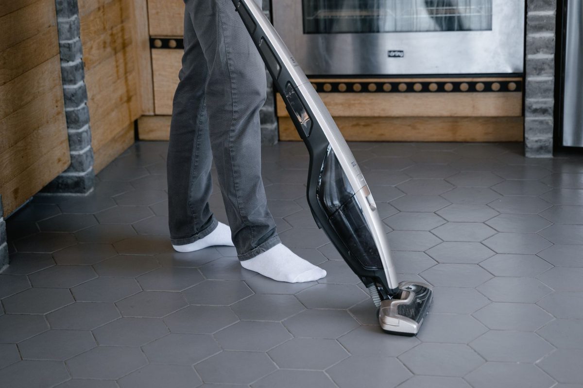 Personne passant l'aspirateur balai sans fil dans un salon