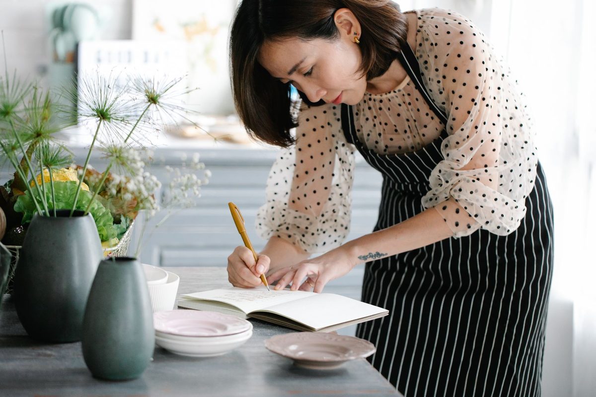 Femme rédigeant son carnet de menus dans la cuisine